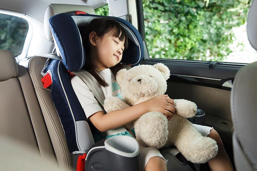 little girl sleeping in car seat while holding a teddy bear